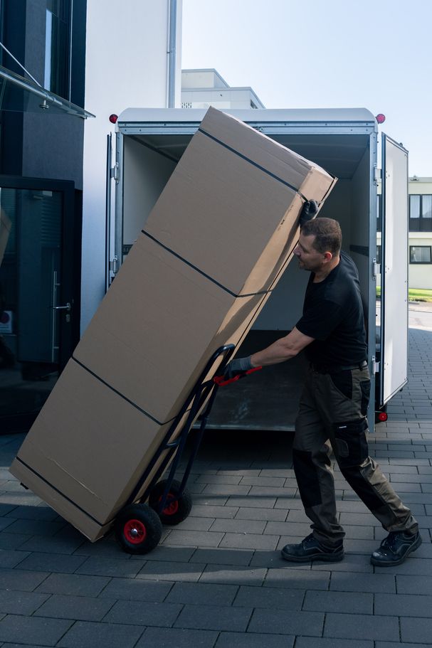 Monteur liefert Küchenmöbel per Sackkarre aus Transporter